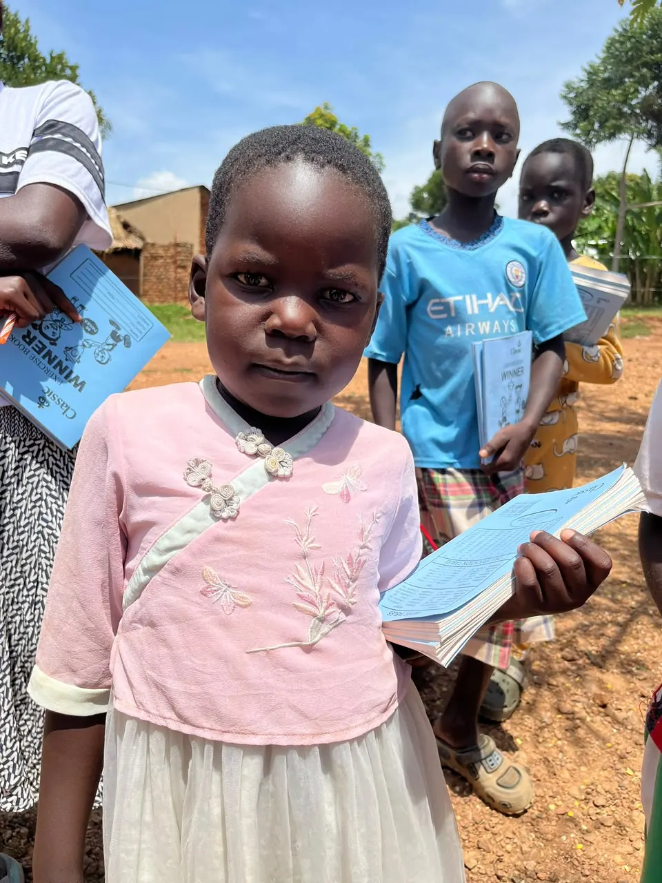 Child holding learning materials in Bumbo village
