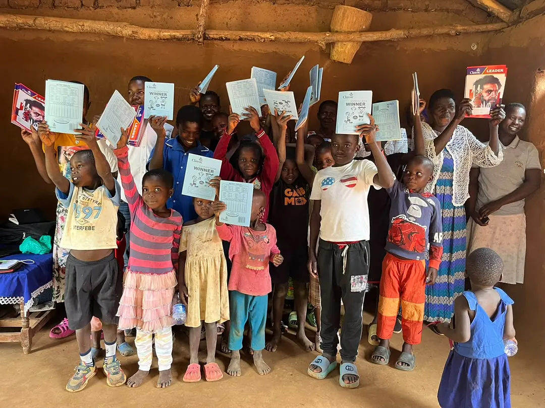 Children in Bumbo village holding learning materials during a Child of Hope community visit